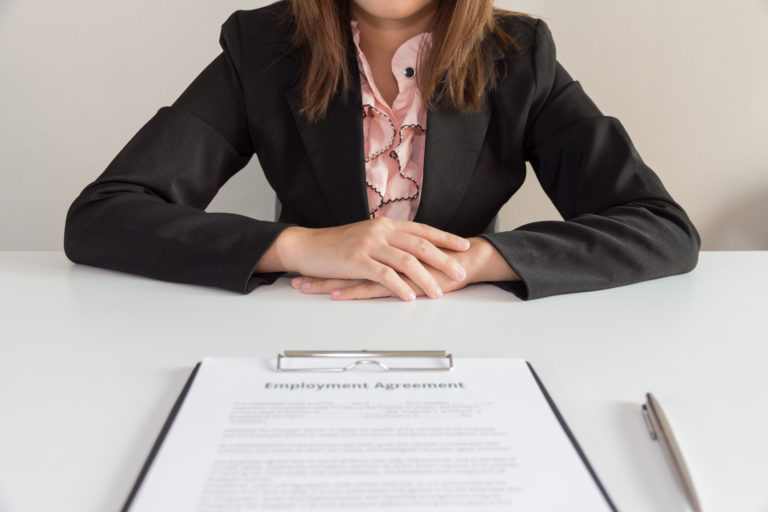 Businesswoman sitting with employment agreement in front of her.