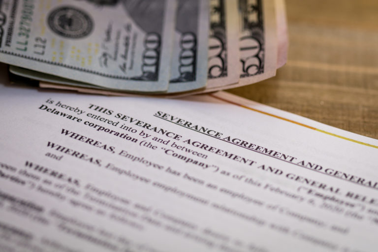Image of a severance agreement, slightly blurred, and $300 cash above the agreement.